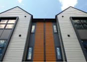 Thumbnail 10 of 29 - A modern house with a combination of grey and brown siding.