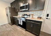 Thumbnail 14 of 29 - A kitchen with black cabinets and a stainless steel refrigerator.