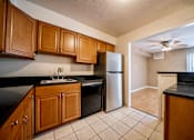 Thumbnail 12 of 18 - A kitchen with wooden cabinets and a black counter top at Westwood Meadows, Westlake, OH, 44145