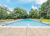 Thumbnail 31 of 35 - A large outdoor swimming pool surrounded by trees and lounge chairs.