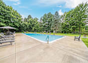 Thumbnail 33 of 35 - A large outdoor swimming pool surrounded by trees and lounge chairs.