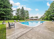 Thumbnail 29 of 35 - A large outdoor swimming pool surrounded by trees and a wooden deck.