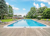 Thumbnail 30 of 35 - A large outdoor swimming pool surrounded by trees and lounge chairs.