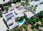 Thumbnail 13 of 14 - Aerial drone view of Rose North Apartments showing solar panels, energy efficient roof, and courtyard with pool.