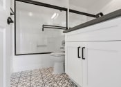 Thumbnail 13 of 19 - White bathroom with shower, tub, and tiled floor.