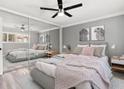 Thumbnail 6 of 24 - Carpeted bedroom with ceiling fan and large mirrored closet.