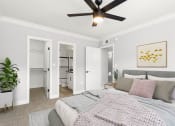 Thumbnail 6 of 22 - Carpeted bedroom with ceiling fan and private bathroom.