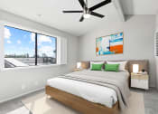 Thumbnail 9 of 23 - Carpeted bedroom with ceiling fan and large window for natural light.