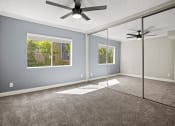 Thumbnail 10 of 15 - Carpeted bedroom with ceiling fan and large mirrored closet.