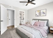 Thumbnail 3 of 23 - Carpeted bedroom with ceiling fan and private bathroom.