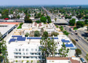 Thumbnail 20 of 20 - Aerial drone view of Chateau Encino showing energy-efficient white roof, solar panels, and access to 101 freeway.
