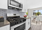 Thumbnail 1 of 23 - Blue tiled kitchen with stainless steel oven, microwave, and fridge.