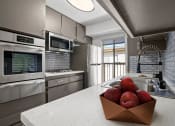 Thumbnail 3 of 15 - Blue tiled kitchen with stainless steel oven, microwave, fridge, and fixtures.