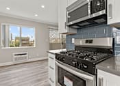 Thumbnail 3 of 15 - Blue tiled kitchen with stainless steel oven, microwave, and fridge.