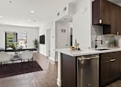 Thumbnail 6 of 23 - Tiled kitchen with stainless steel appliances and view of hardwood floored living room and balcony.
