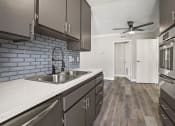 Thumbnail 2 of 15 - Blue tiled kitchen with stainless steel oven, microwave, and fixtures.