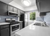 Thumbnail 2 of 28 - Tiled kitchen with stainless steel oven, microwave, and fridge.
