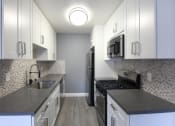 Thumbnail 4 of 22 - Kitchen with quartz stone counters and stainless steel microwave, oven, fridge, and fixtures.