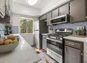 Thumbnail 1 of 28 - Tiled kitchen with stainless steel oven, microwave, and fridge.