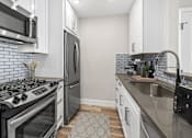 Thumbnail 4 of 31 - Blue tiled kitchen with stainless steel fridge, oven, and fixtures.