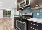 Thumbnail 2 of 22 - Blue tiled kitchen with stainless steel oven and microwave.
