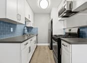 Thumbnail 10 of 27 - Blue tiled kitchen with stainless steel fridge, oven, and microwave.