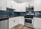 Thumbnail 7 of 24 - Blue tiled kitchen with stainless steel fridge, oven, and microwave.