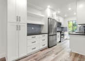 Thumbnail 10 of 25 - Blue tiled kitchen with stainless steel fridge, oven, and microwave.