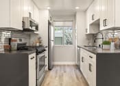 Thumbnail 3 of 25 - Tiled kitchen with stainless steel microwave, oven, fridge, and fixtures.