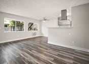Thumbnail 6 of 16 - Large hardwood floored living room with ceiling fan over dining room.