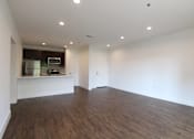 Thumbnail 15 of 23 - Hardwood floored living room with can lights and view of kitchen.