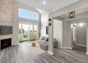Thumbnail 6 of 27 - Hardwood floored living room with view of stone accent wall, fireplace, and high third-floor ceilings.
