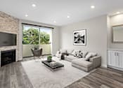 Thumbnail 14 of 24 - Hardwood floored living room with view of stone accent wall, fireplace, and private balcony.