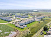 Thumbnail 1 of 23 - A large building complex surrounded by a green field.