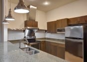 Thumbnail 32 of 35 - Organic finishes in apartment kitchen with stunning vent hood and stainless steel appliances at The Mosaic on Broadway, San Antonio, TX