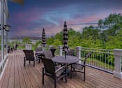 Thumbnail 1 of 50 - A deck with a table and chairs overlooking a forest.