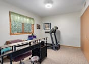 Thumbnail 18 of 27 - A room with a treadmill and a desk.