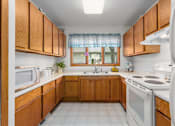 Thumbnail 25 of 27 - A kitchen with wooden cabinets and white appliances.