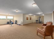 Thumbnail 18 of 50 - A room with a brown chair and exercise equipment.