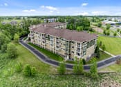 Thumbnail 6 of 50 - A large apartment complex with a curved driveway in front.