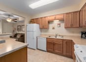 Thumbnail 22 of 50 - A kitchen with a white refrigerator and brown cabinets.