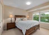 Thumbnail 24 of 50 - A bedroom with a bed, nightstands, and a window overlooking a green landscape.
