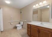Thumbnail 25 of 50 - A bathroom with a toilet, sink, and mirror.