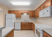 Thumbnail 26 of 50 - A kitchen with white appliances and wooden cabinets.