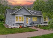 Thumbnail 1 of 27 - A house with a grey exterior and a white door is shown.