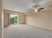 Thumbnail 29 of 50 - A room with a ceiling fan and carpeted floor.
