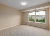 Thumbnail 31 of 50 - A room with a large window and carpeted floor.