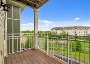 Thumbnail 37 of 50 - A balcony with a white railing overlooks a grassy area and apartment buildings.