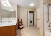 Thumbnail 48 of 50 - A bathroom with a sink, mirror, and a washer and dryer.