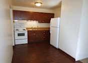 Thumbnail 4 of 7 - an empty kitchen with white appliances and wooden cabinets